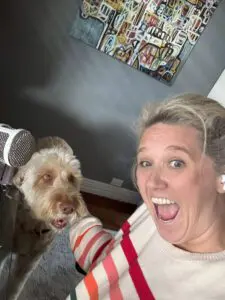 Meg Coffey taking a selfie with a dog beside a podcast microphone